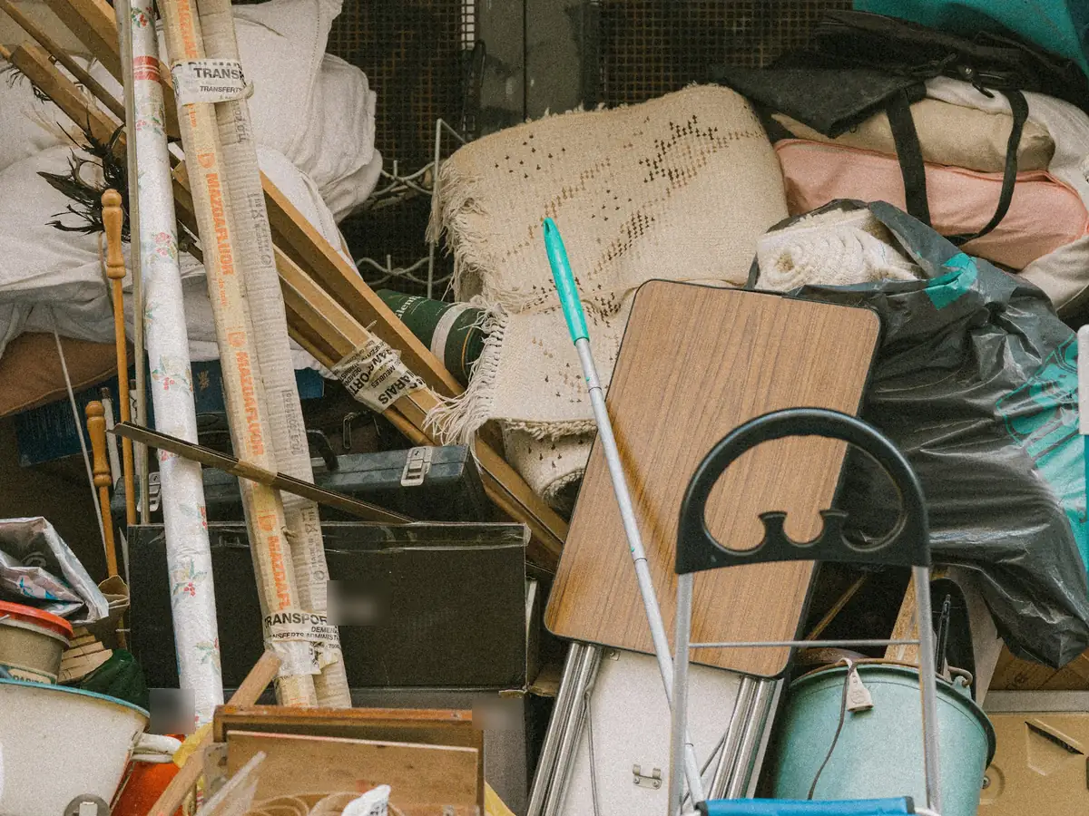 A large pile of household junk, including rolled rugs, boards, bags, a folding table and boxes.