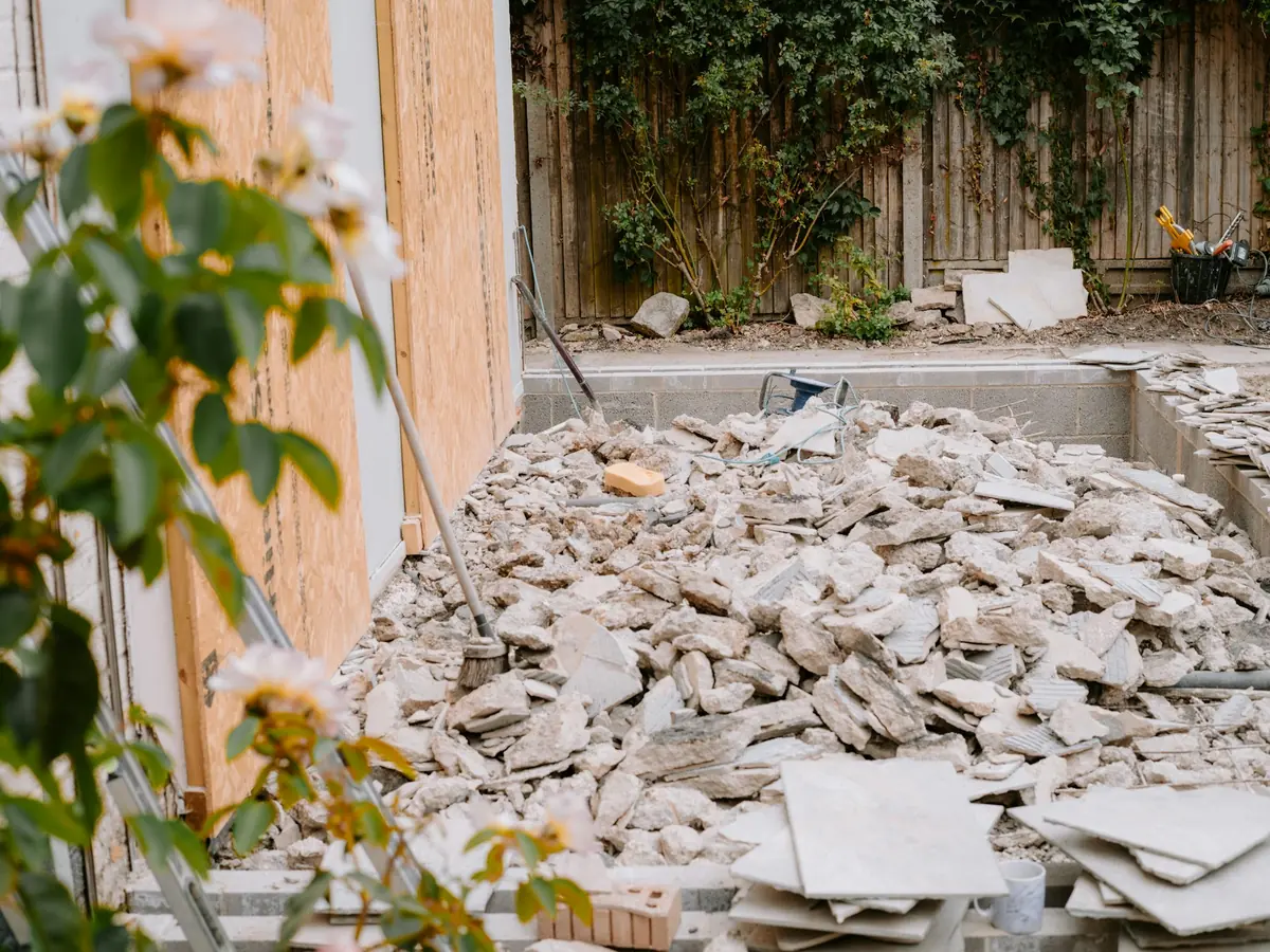 A pile of broken concrete and tile rubble in a backyard.