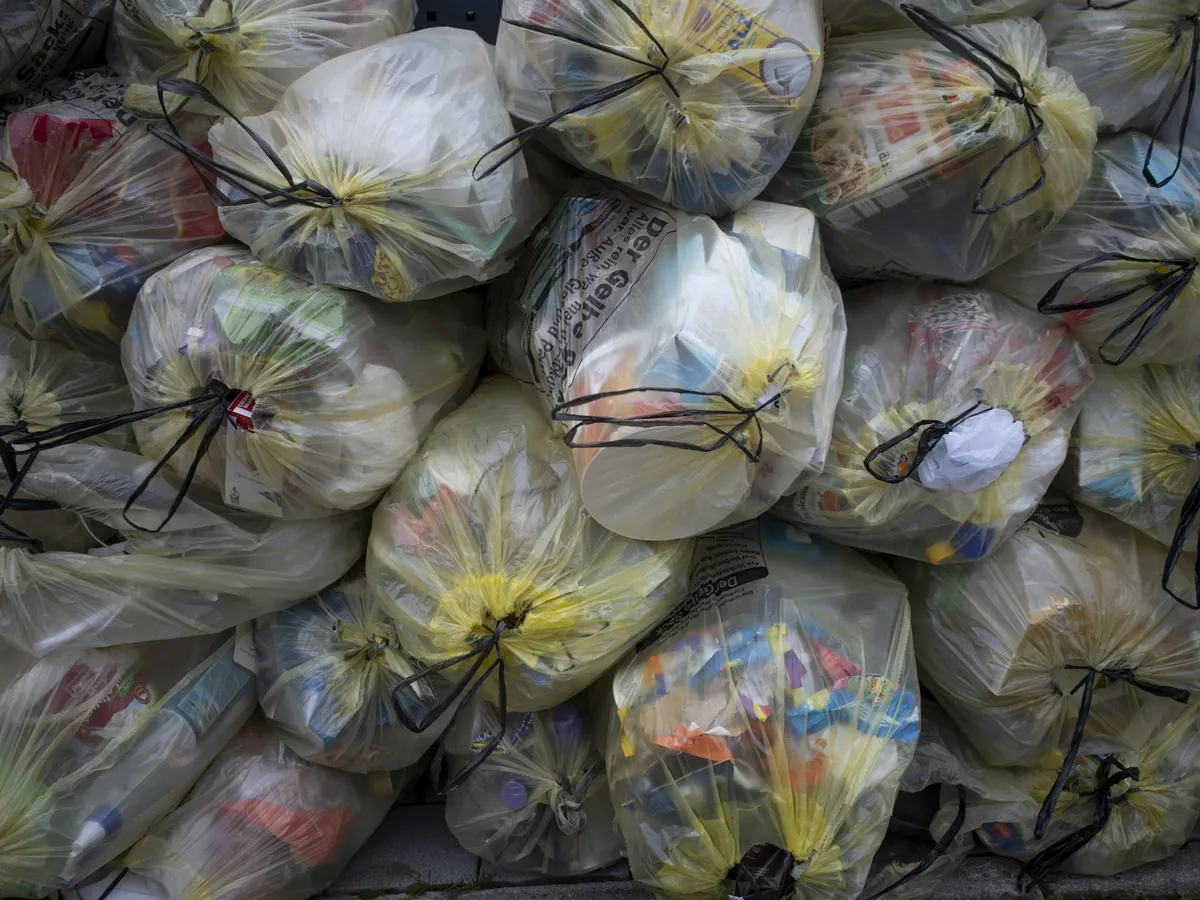 A large pile of tied-up trash bags stacked together.